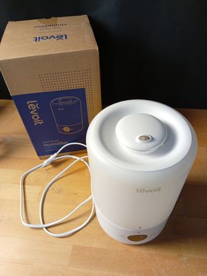 un humidificateur blanc posé sur une table en bois à côté d'une boîte
