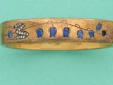 un gros plan d'une bague en or ornée d'oiseaux et de fleurs