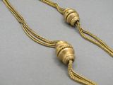 a close up of a gold necklace with two beads on a chain