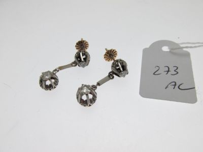 three silver and gold earrings with a price tag on a white table