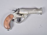 un gros plan d'un pistolet posé sur une surface blanche, avec une crosse en bois