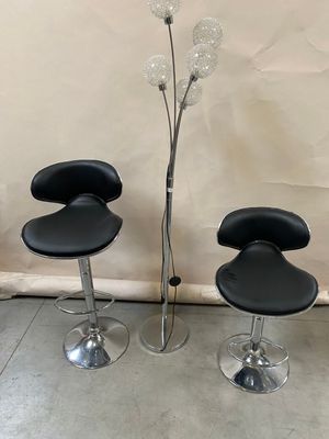 three black leather bar stools and a glass vase with a flower in it