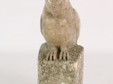 statue of a bird perched on a rock on a white background