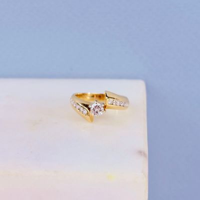 une bague en or sertie de deux diamants, posée sur un bloc de marbre