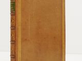 an old book with a brown cover sitting on top of a white table