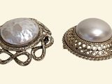 pair of earrings with pearls and filigrees on a white background