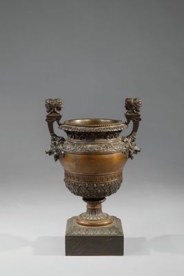 une urne antique en bronze à deux anses, posée sur un socle en marbre