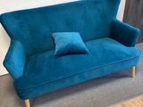 un canapé en velours bleu turquoise sur lequel sont posés deux coussins