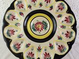 a black and yellow plate with red flowers on it