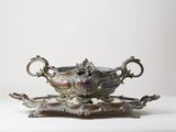 a silver bowl on a stand on a white surface