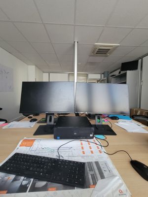 a desk with a keyboard, monitor, mouse, and other items on it