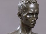 a bronze bust of a man on a wooden stand