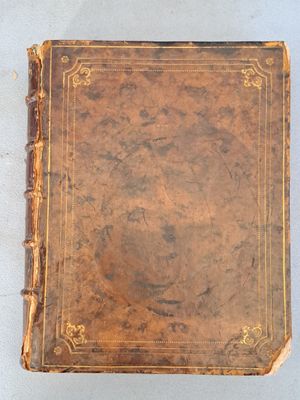 un vieux livre marron posé sur une table blanche