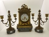 three candles and a clock sitting on a table