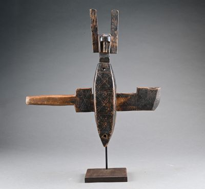 une sculpture en bois représentant un avion à deux ailes, posée sur un socle
