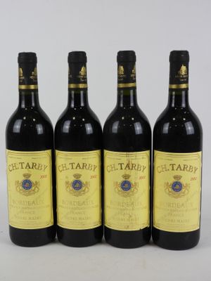 quatre bouteilles de vin sont alignées sur une surface blanche
