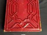 an old red book with a gold border and a black background