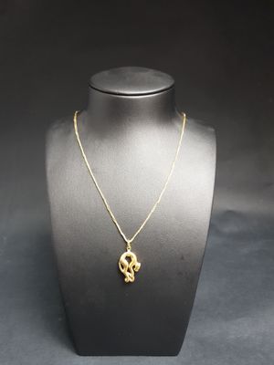 a gold necklace with a skull pendant on a mannequin