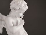 a white statue of an angel with a finger on his lips