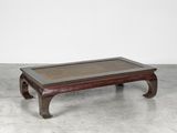 an old wooden coffee table with a glass top on a concrete floor