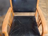 a wooden chair with a black leather seat on a wooden floor