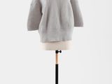 un pull gris posé sur un mannequin, devant un fond blanc