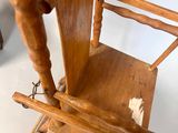 a wooden rocking chair with a wooden seat and a wooden arm rest