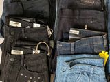 a lot of jeans that are stacked together on a table
