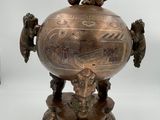 an antique bronze urn with a bird on top of it on a pedestal