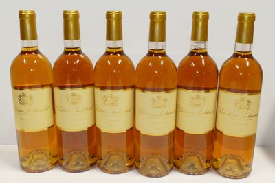 six bouteilles de vin sont alignées sur une surface blanche