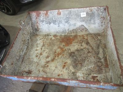 une caisse métallique rouillée posée sur une palette en bois