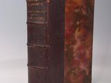un vieux livre posé sur une table blanche à côté d'un mur blanc