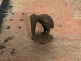 a small elephant figurine sitting on top of a piece of wood