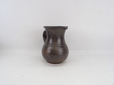 un petit vase brun posé sur une surface blanche