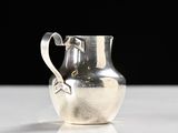 a silver pitcher sitting on a table with a black background