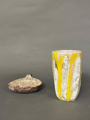 un vase jaune et blanc et un rocher sur une surface grise
