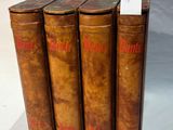 four old books are lined up in a row on a white surface