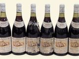 six bouteilles de vin sont alignées sur une surface blanche