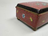 a small red box with flowers on it on a white surface