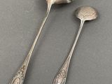 two silver spoons and a spoon rest on a table