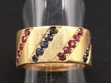 une photo en gros plan d'une bague en or sertie de pierres bleues et rouges