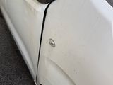 a small white car with a broken door on the side of the road