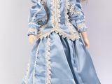 une image représentant une poupée portant une robe bleue et un chapeau
