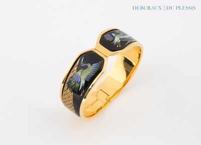 une image représentant une bague en or sur laquelle figure un oiseau noir et vert