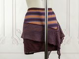 purple and orange striped skirt on a mannequin stand in front of a white wall