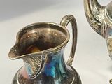 two silver teapots sitting next to each other on a table