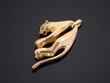 a close up of a gold cat broochle on a black surface