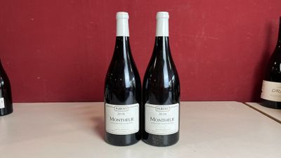 trois bouteilles de vin sont posées sur un comptoir devant un mur rouge
