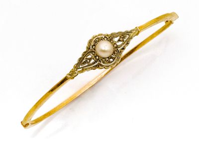un gros plan sur un bracelet en or orné d'une perle au centre