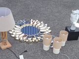 a table with a lamp, vases, a mirror, and other items on it
